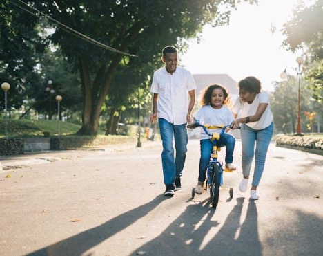 Routine A mother and father teaching their daughter to ride a bike.