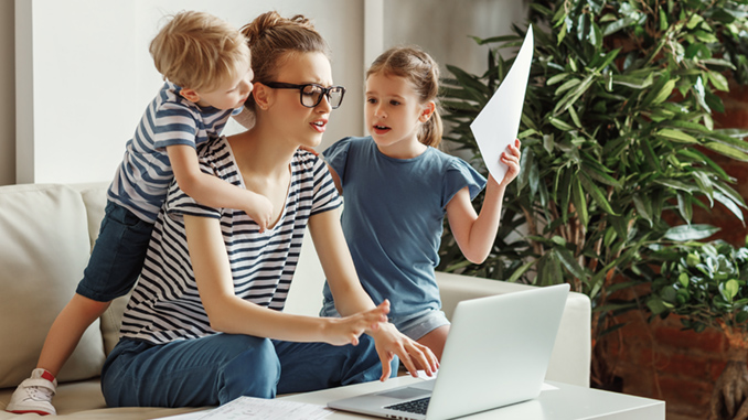 Tired,Young,Mother,Sitting,On,Sofa,And,Working,With,Laptop