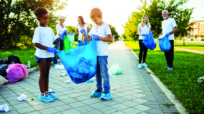 Volunteers with garbage bags cleaning up garbage outdoors - ecology concept.